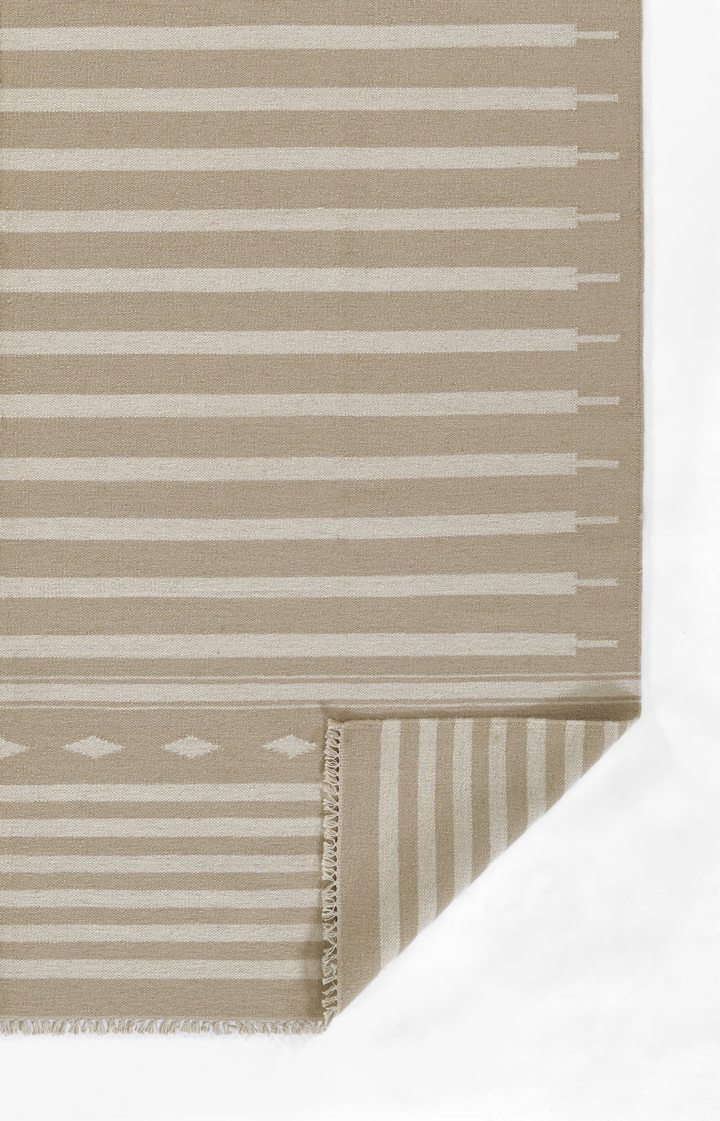 Beige flat-weave rug with white horizontal stripes and a diamond motif near the edge; folded corner shows fringe.