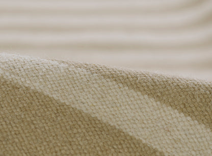 Beige woven rug close-up with a textured surface and soft folds, linen-like material.