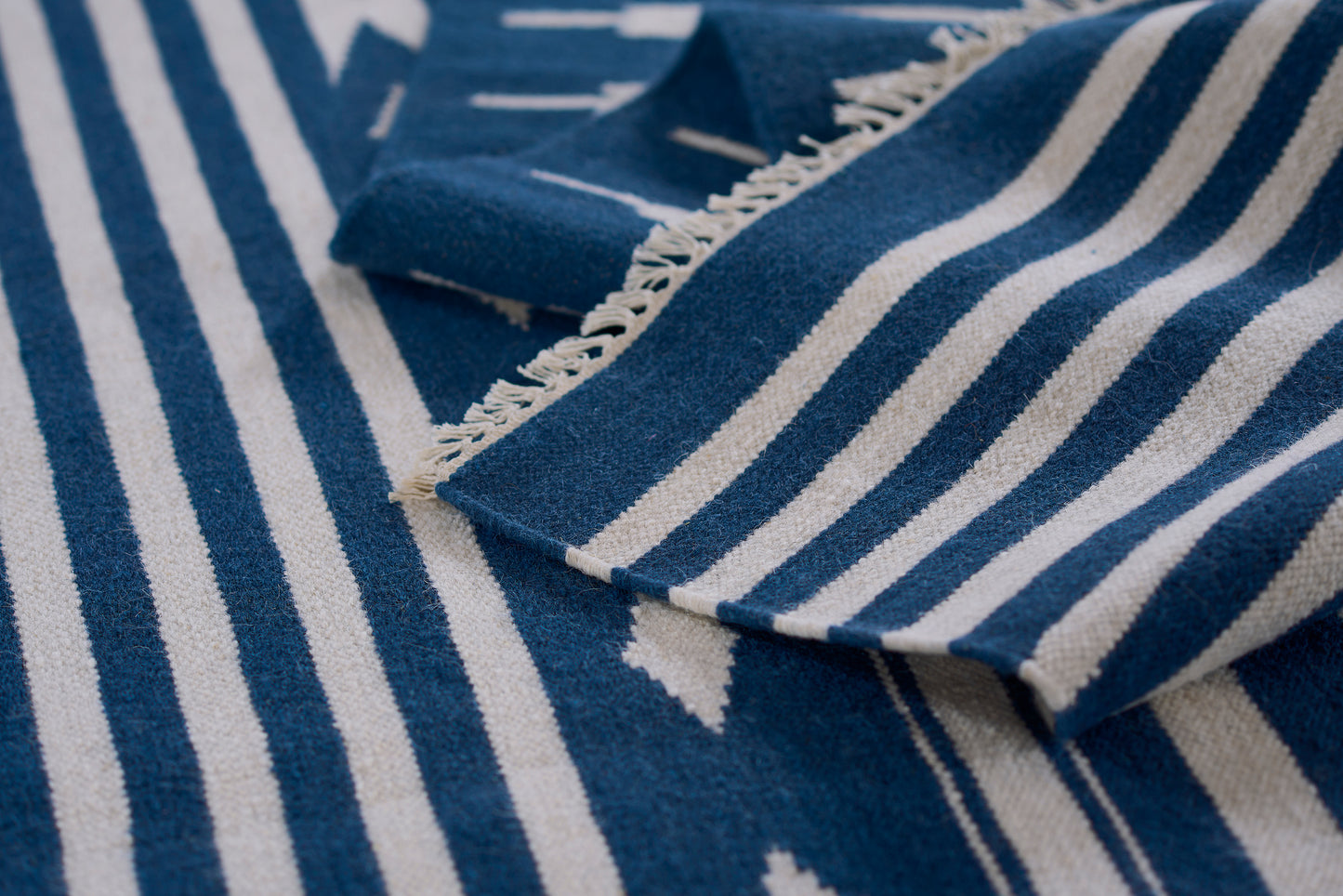 Blue and white striped woven rug with fringe edges.