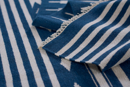 Blue and white striped woven rug with fringed edges, close-up.