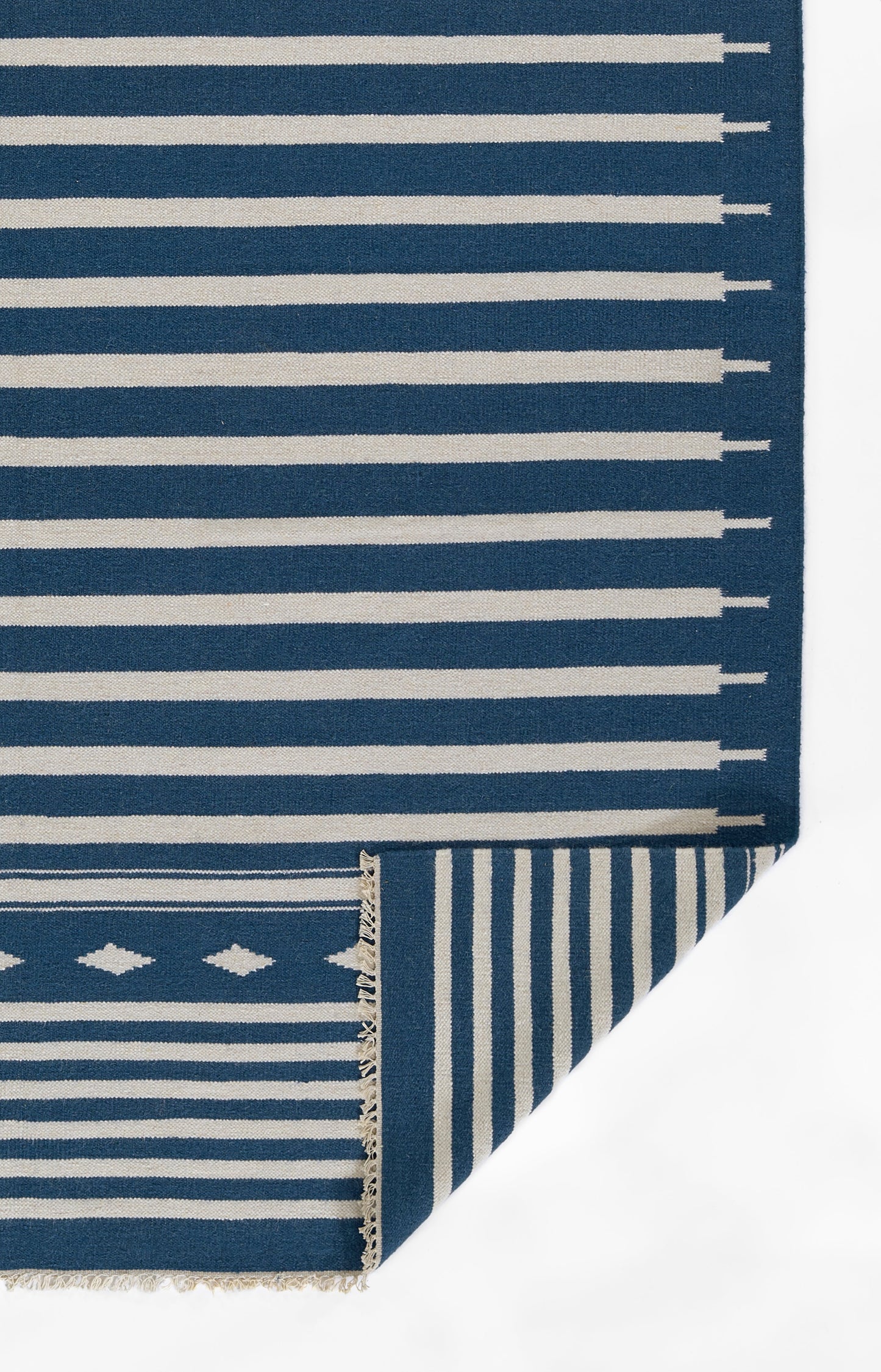 Navy blue woven rug runner with white stripes; folded corner shows blue-and-white geometric diamonds and vertical stripes.
