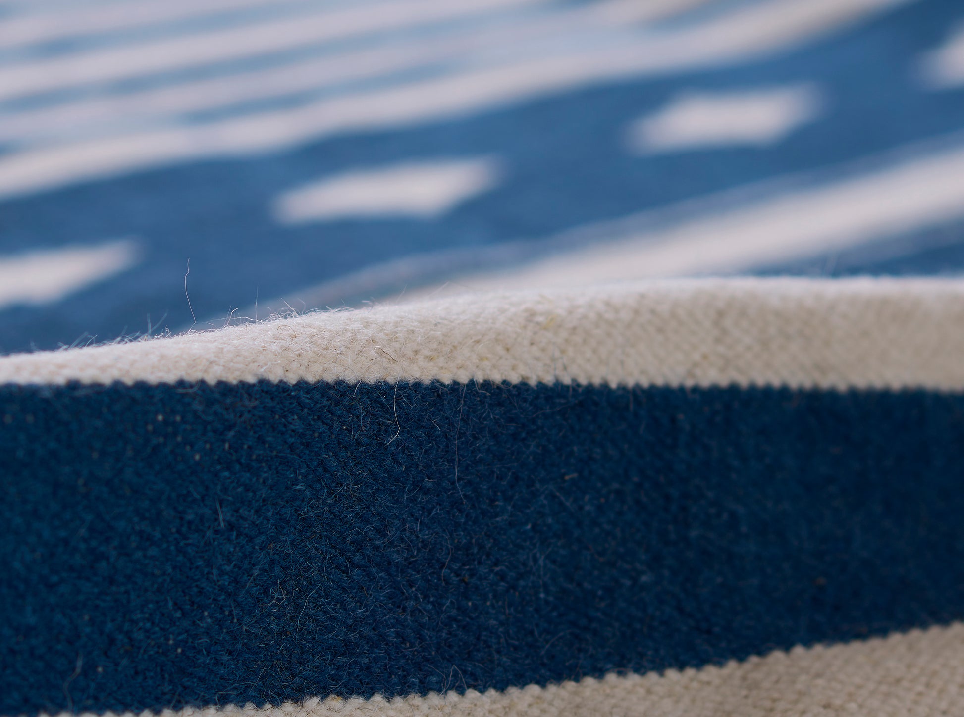 Close-up of blue and cream striped woven rug runner with textured fibers.
