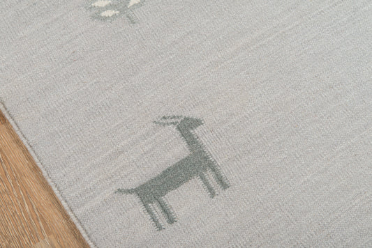 Light gray flatwoven runner rug with teal deer silhouettes; wood floor edge visible.