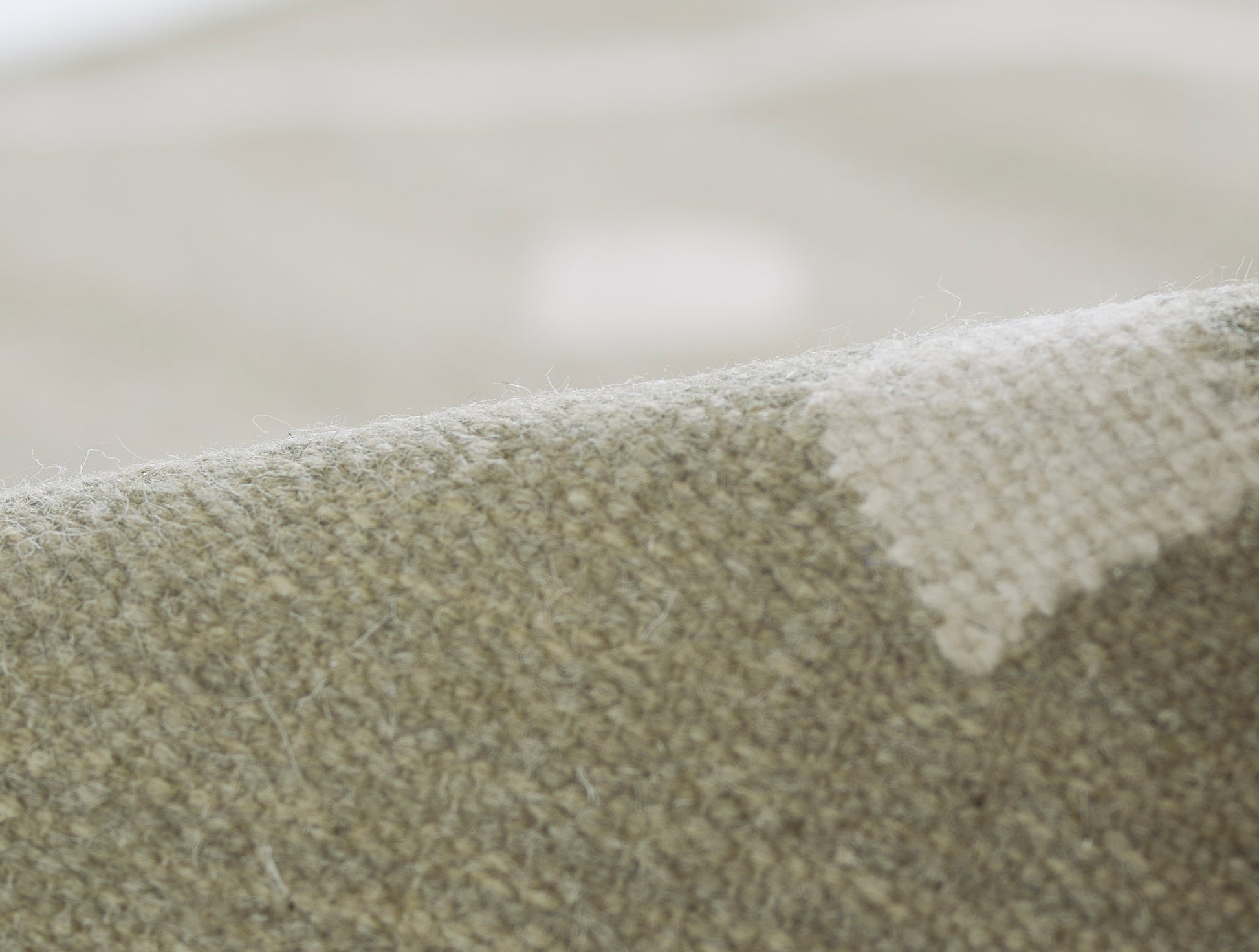 Close-up of a beige-taupe woven rug texture with soft loop fibers, rustic home decor.