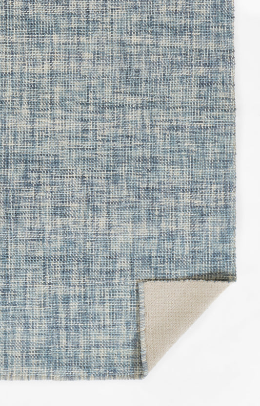 Blue woven rug with abstract cream speckle pattern; flat-weave texture and beige underside at corner.