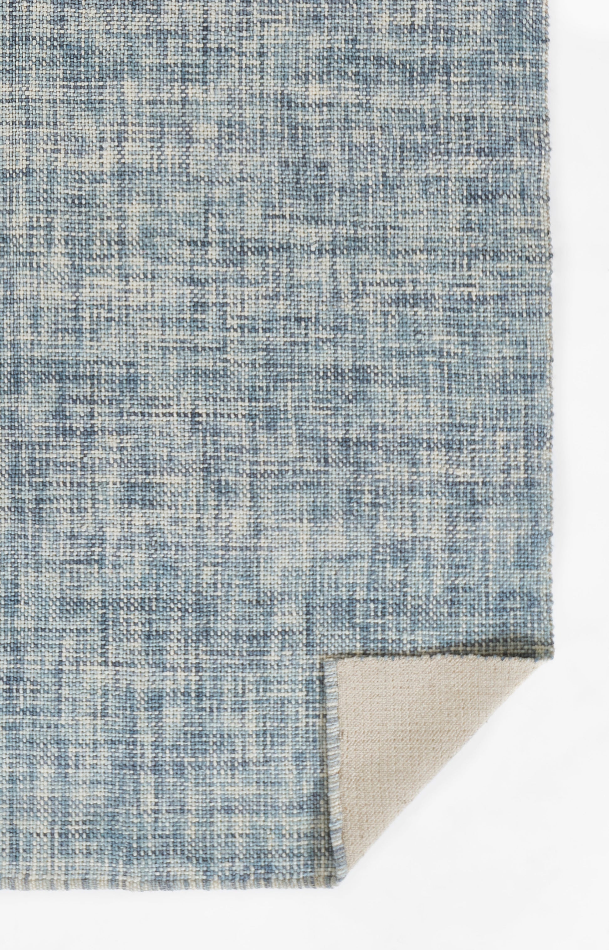 Blue woven rug swatch with a subtle distressed pattern; beige underside peeks from the corner.