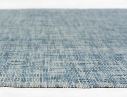 Blue woven area rug with textured yarns in light to medium blue hues, flatweave style, close-up.