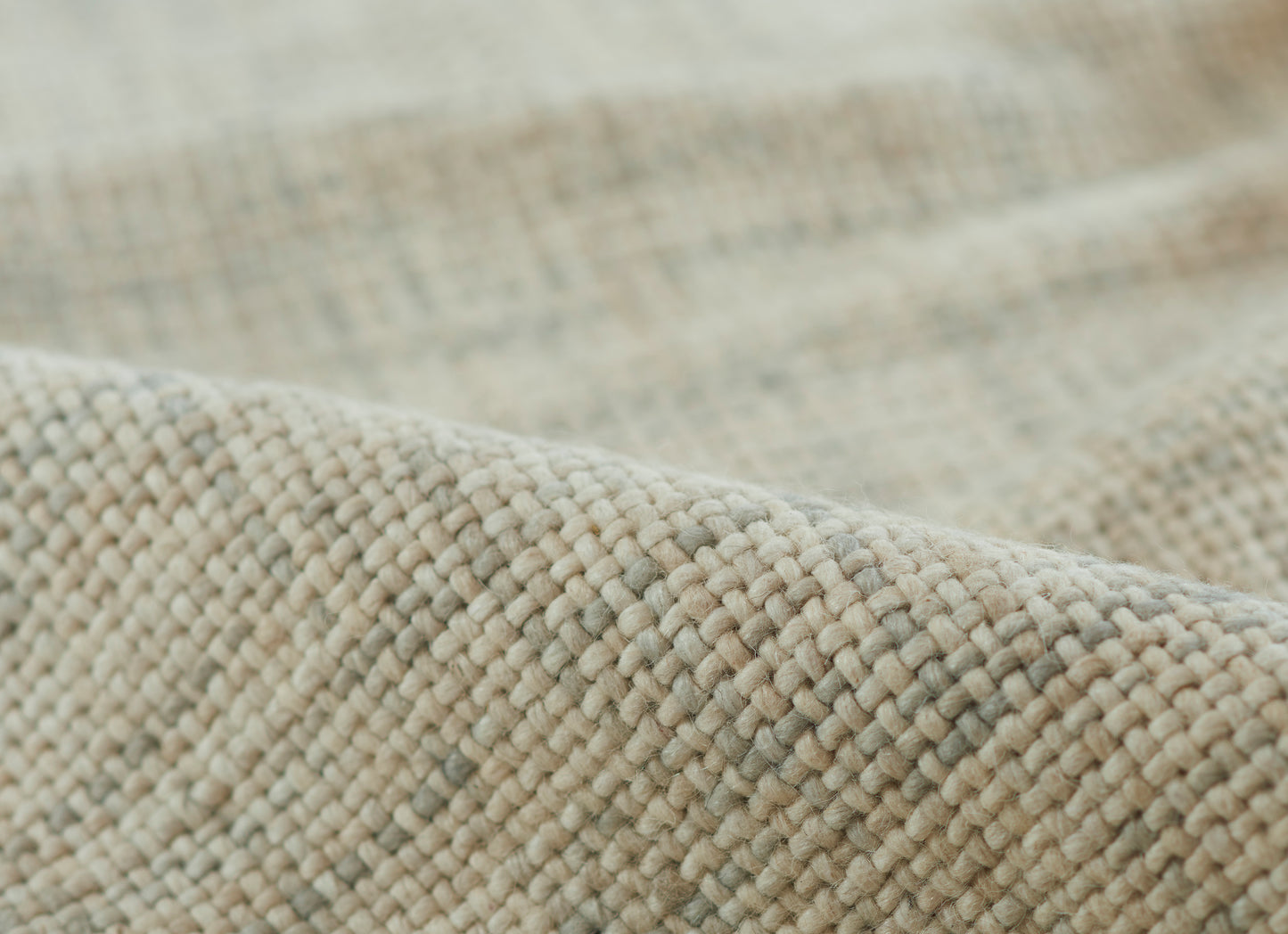 Close-up of beige-gray chunky woven fabric; soft textured textile, ideal for throws or rugs.
