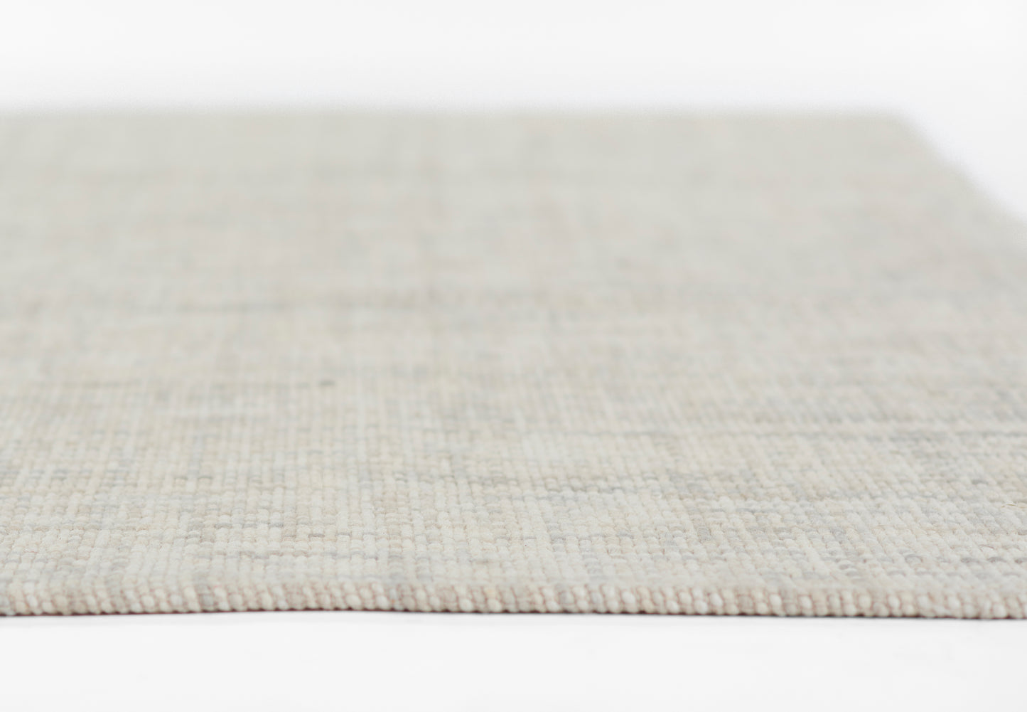Beige flat-weave rug close-up with subtle grid texture; rectangular shape for living room or hallway.
