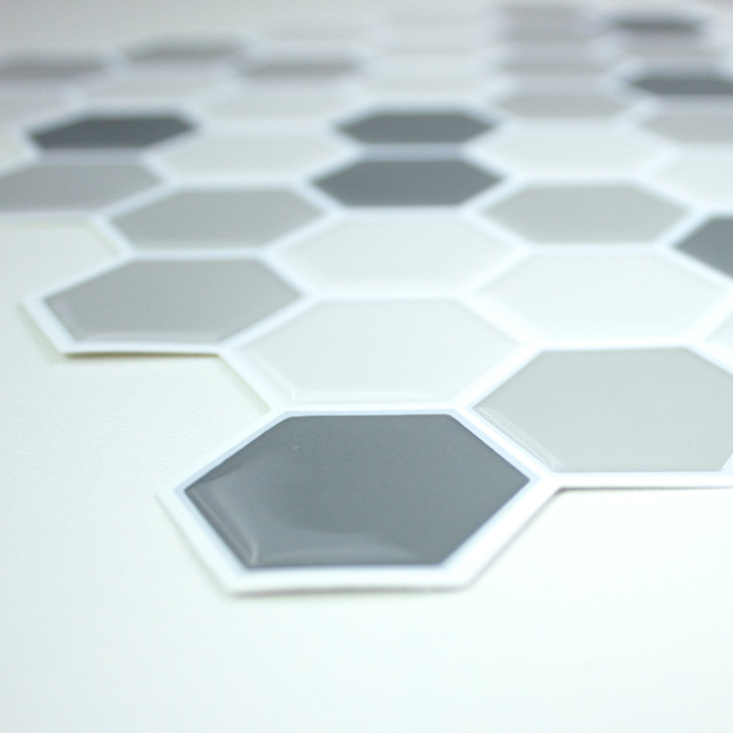 Close-up of gray hexagon tiles with white borders forming a honeycomb mosaic on a pale surface.