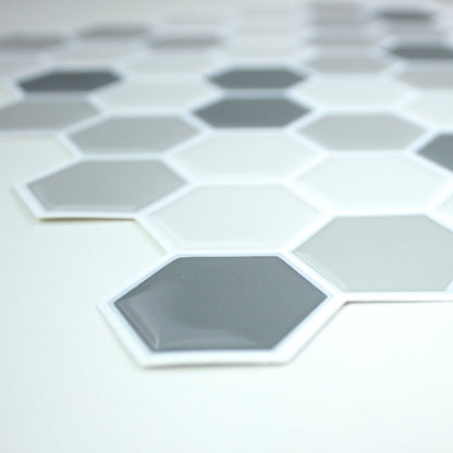 Close-up of gray hexagon tiles with white borders forming a honeycomb mosaic on a pale surface.