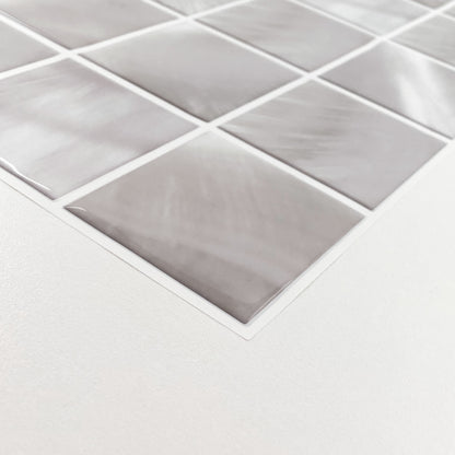 Close-up of light gray marble-pattern square tiles on a mesh sheet, angled on a white surface.