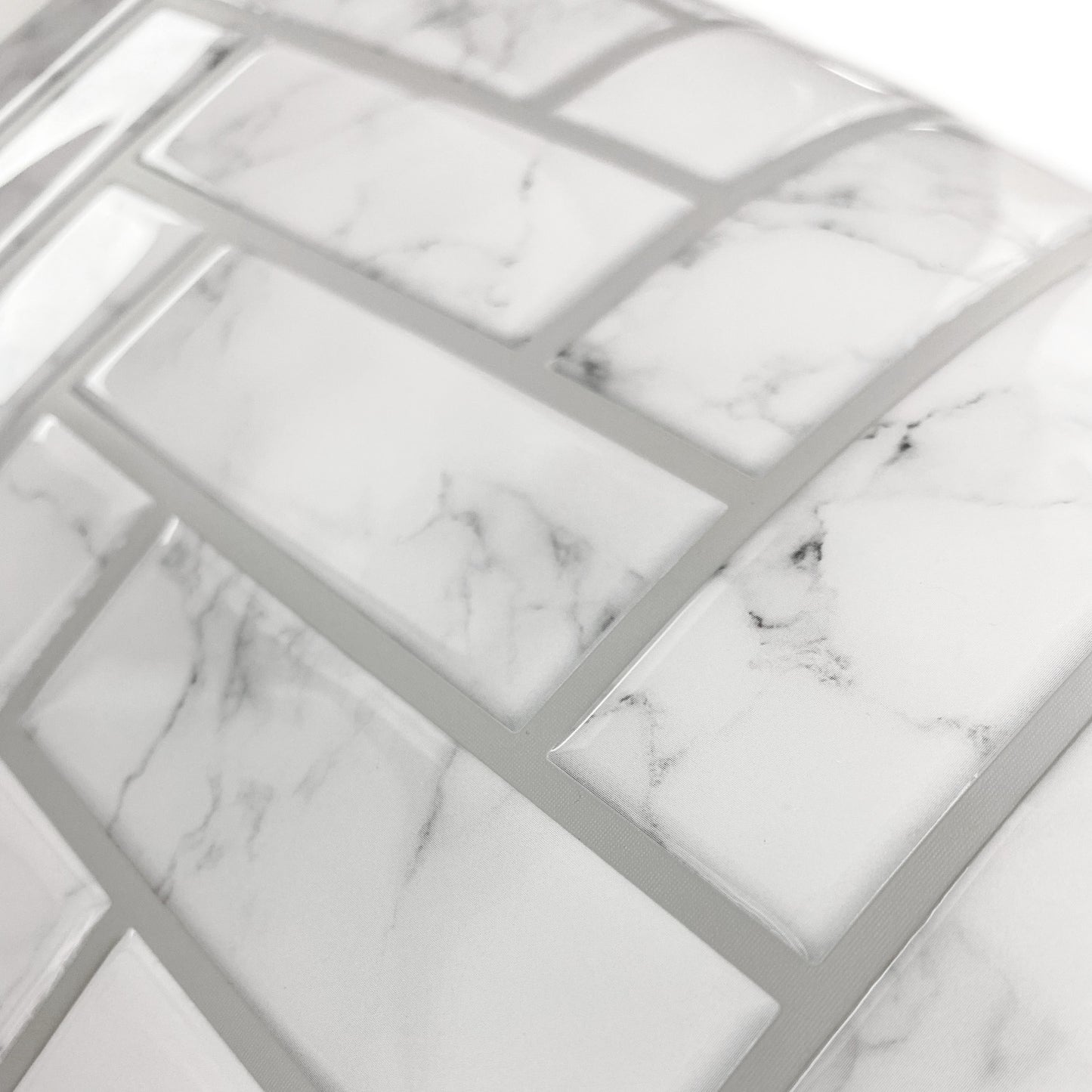 Close-up of marble-look white and gray tile-like wallpaper sheet showing a mosaic pattern and thin gray grout lines.