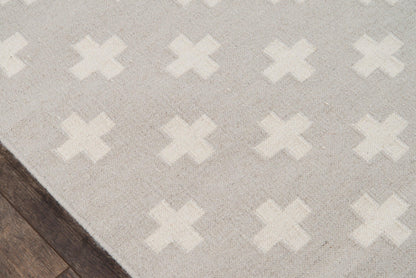 Soft gray area rug with white X-shaped motif, plush texture on dark wood floor.