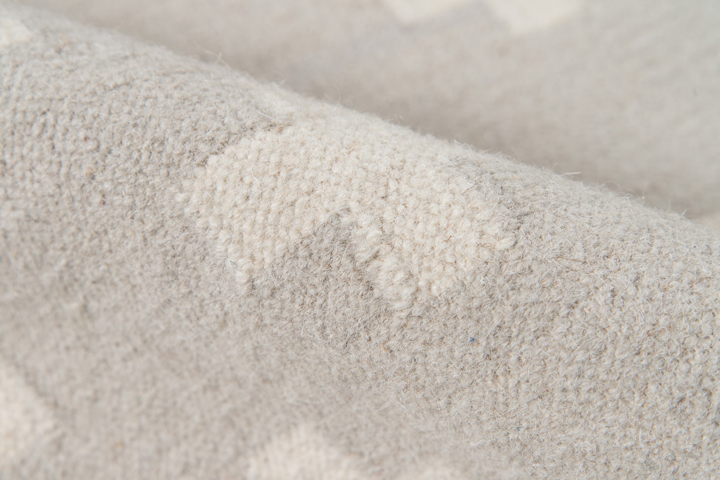 Beige-gray knitted fabric close-up with fuzzy texture, sweater material.