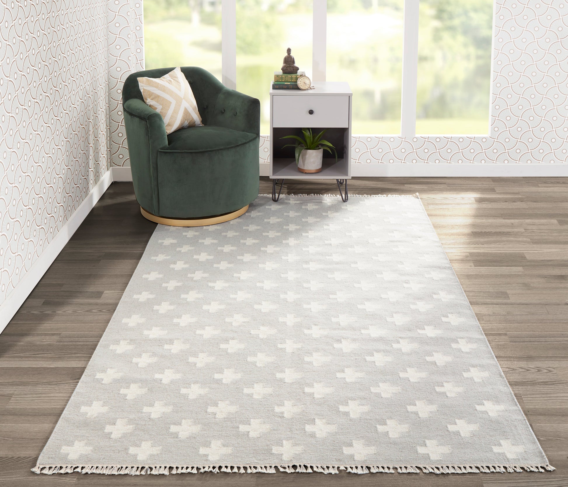 Gray geometric area rug with tassels in a modern living room beside a green velvet swivel chair and white side table.