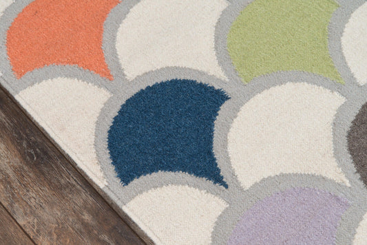 Tufted area rug with arc-shaped color blocks in orange, lime, navy, lavender and cream with gray outlines on a wooden floor.