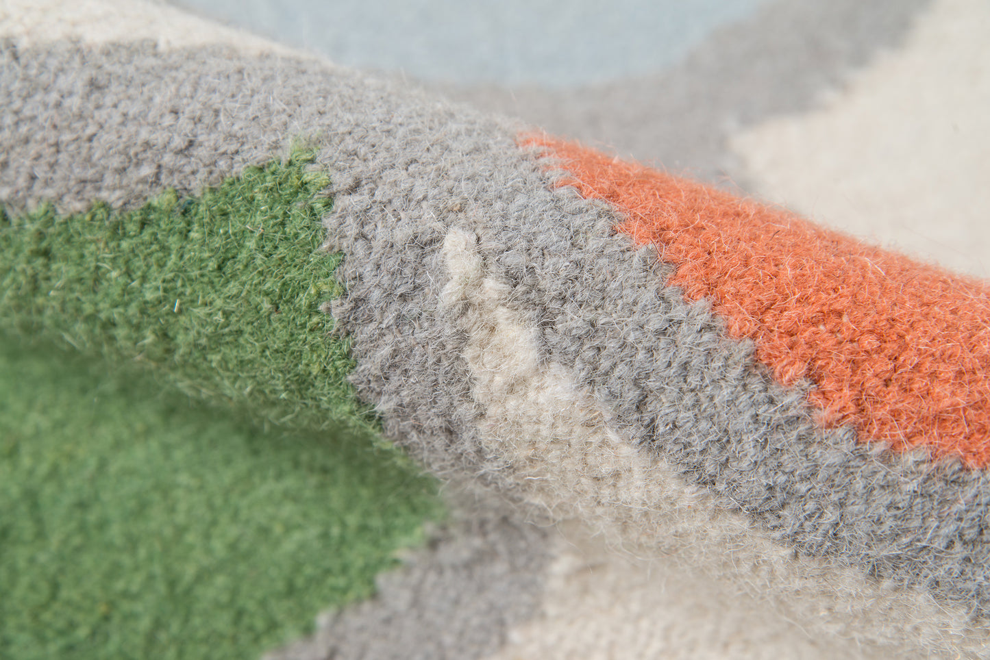 Close-up of a color-block striped rug in green, gray, beige & orange.