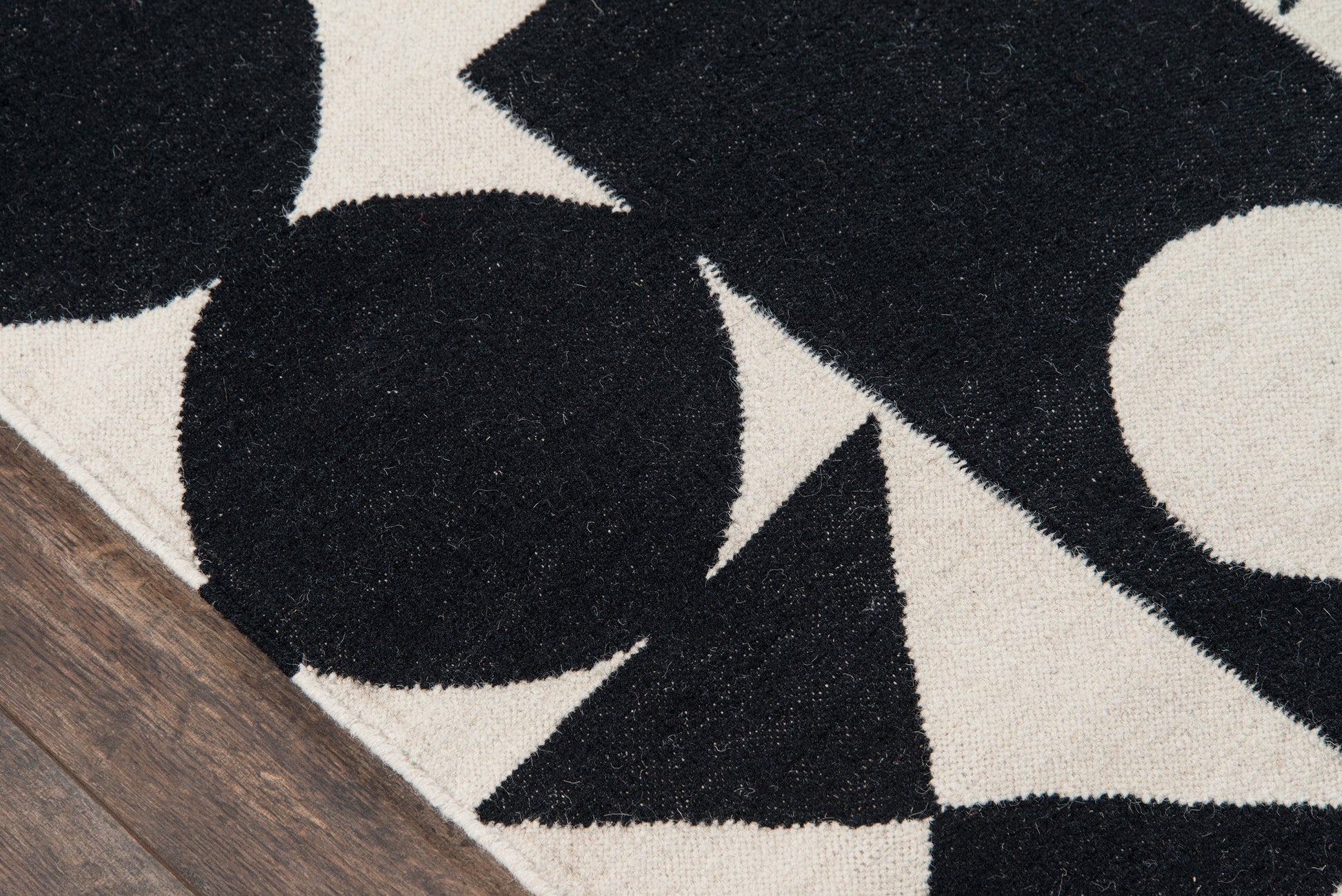 Geometric black and cream rug with bold shapes, plush textured pile, on a wooden floor.