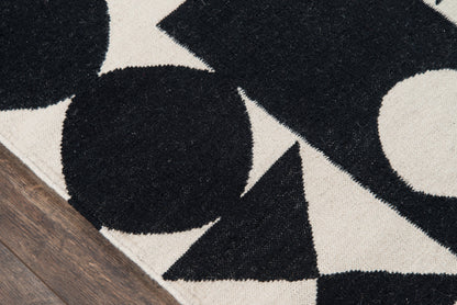 Black and beige geometric rug with circles and triangles on wood floor.