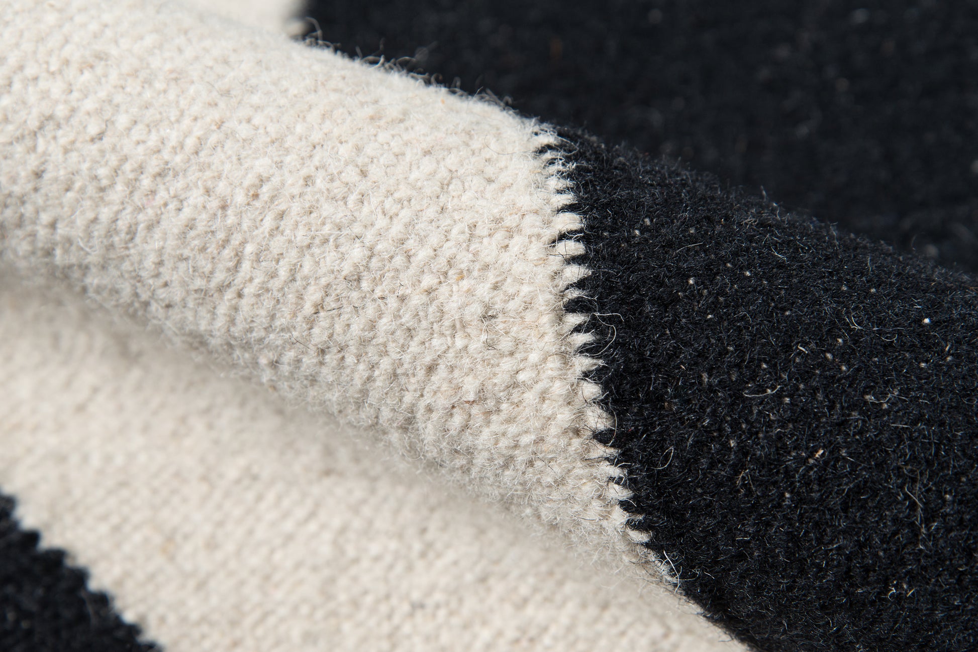 Cream-beige and black boucle rug with a color-block design and chunky fuzzy texture.