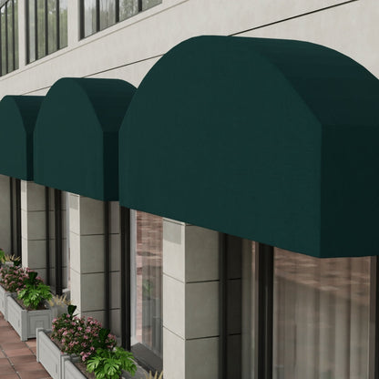 Dark green curved fabric storefront awnings over windows on a beige building; planter boxes line the sidewalk.