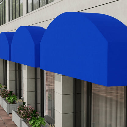 Bright blue curved fabric used for storefront awnings over shop windows on a modern gray building with planter boxes.