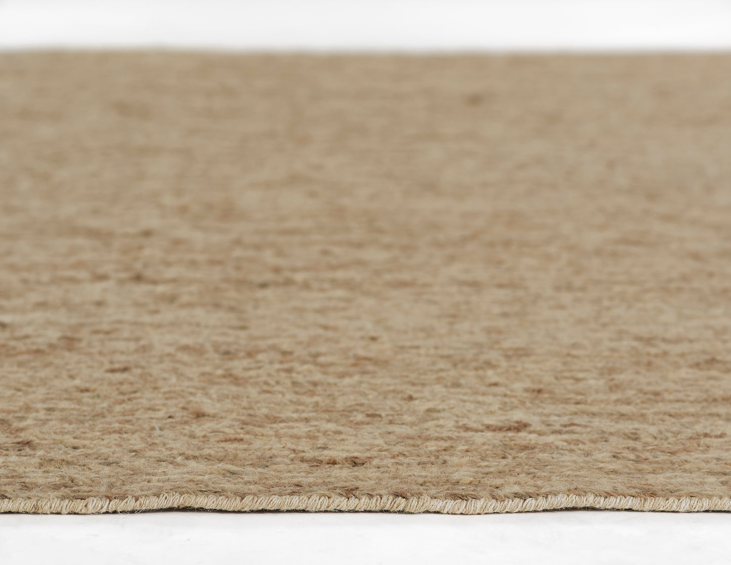 Beige natural-fiber rug with short pile and fringe along the edge.