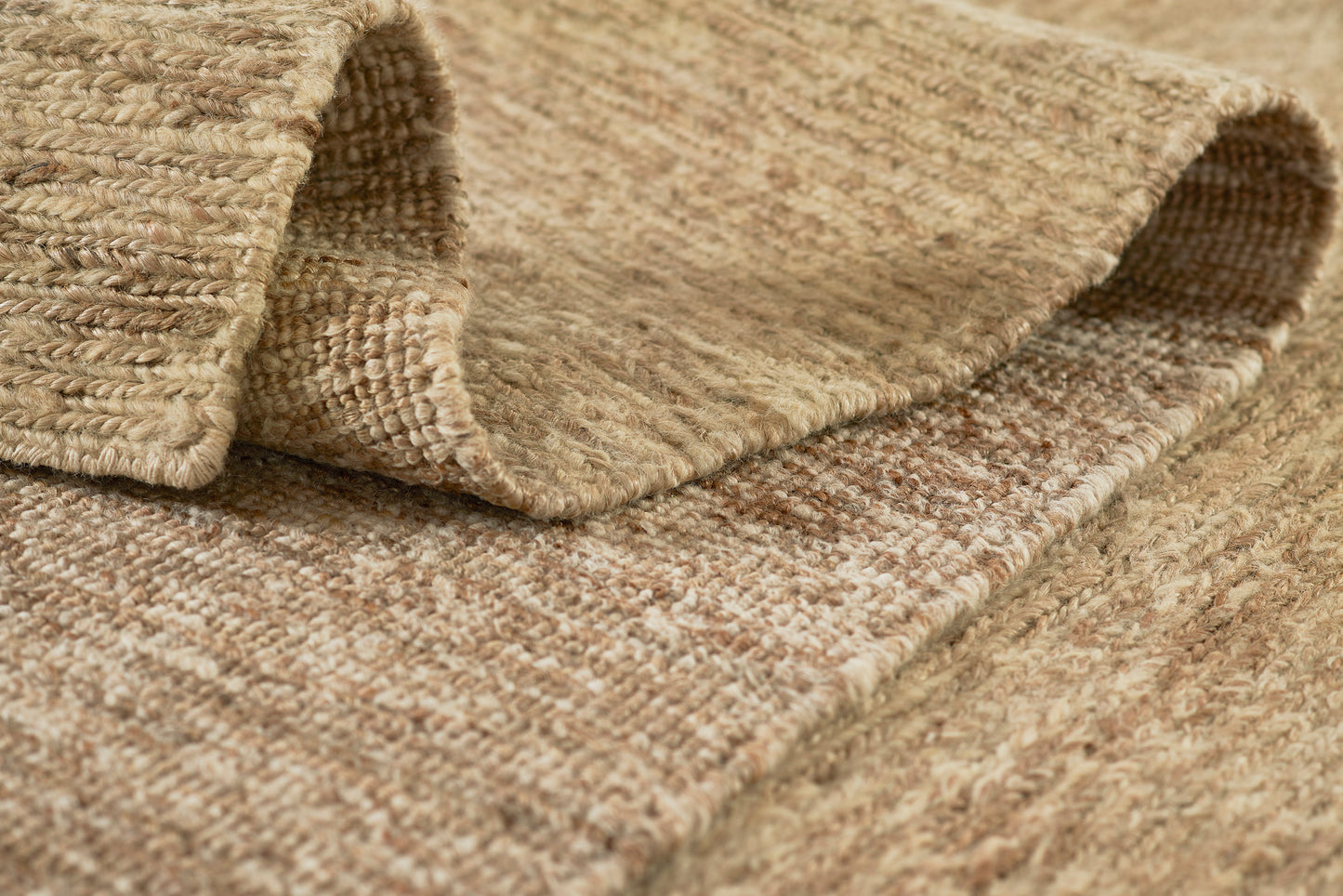 Natural beige woven rug with chunky fibers; textured jute/sisal weave, folded edge, casual rustic decor.