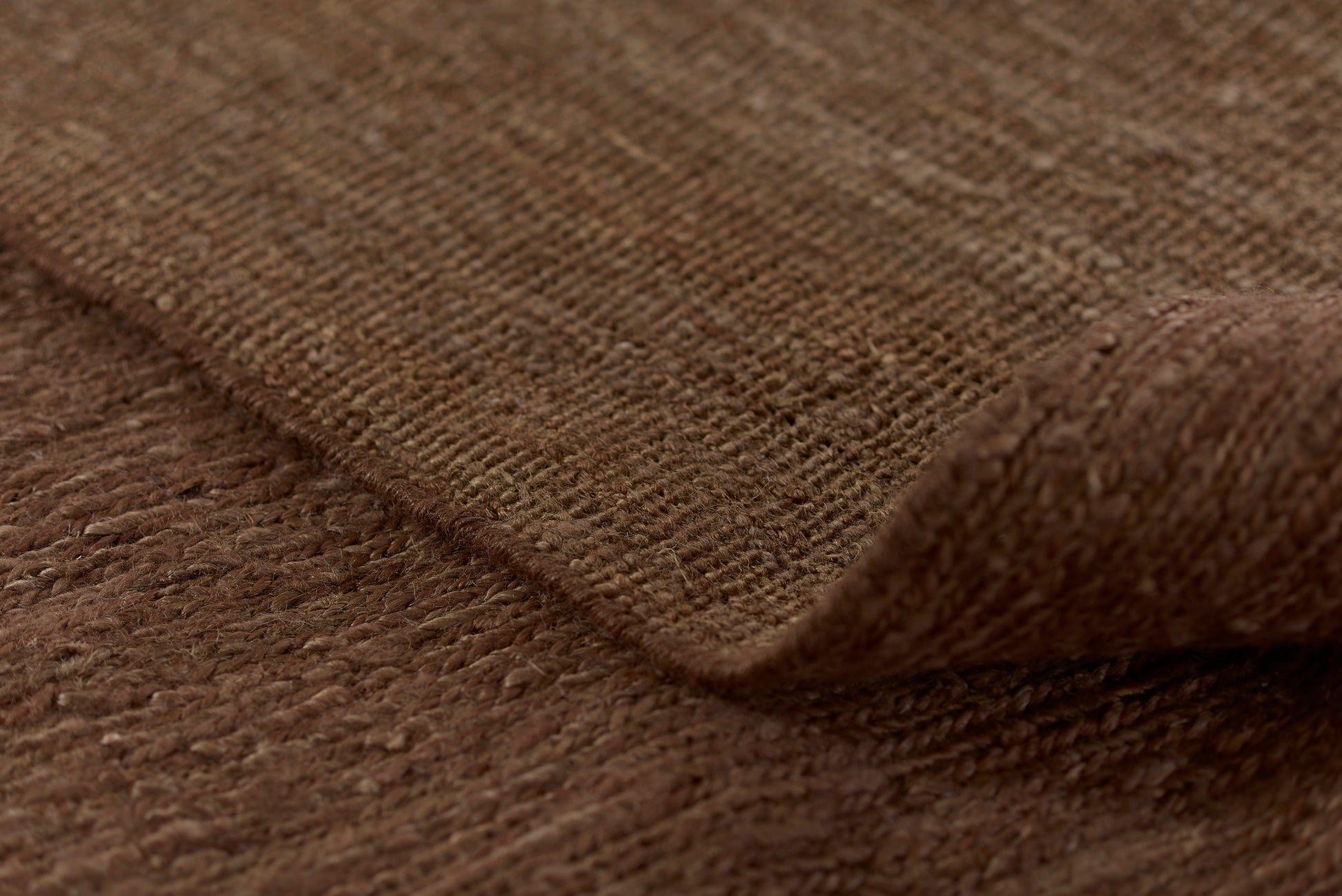 Close-up of brown textured woven fabric with visible weave and folded edge.