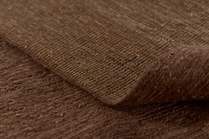 Close-up of brown textured woven fabric with visible weave and folded edge.