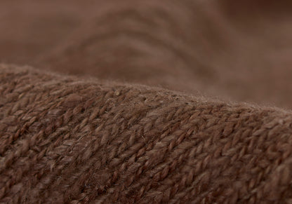 Close-up of brown knitted wool fabric with chunky yarn texture; cozy warm sweater or throw material.