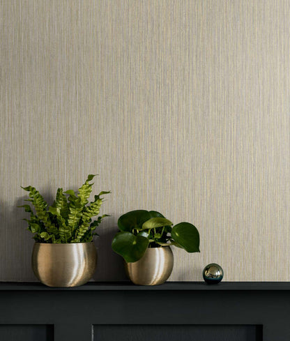 Beige textured wall with a dark shelf, two round gold pots holding fern and pothos, and a small blue-green orb.