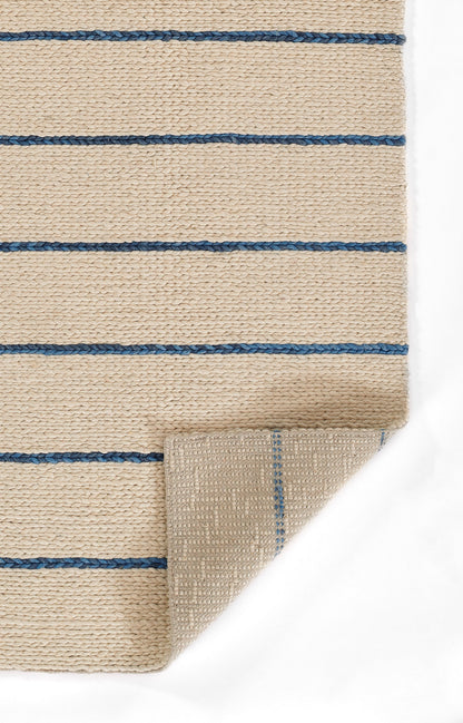 Beige woven jute rug with blue horizontal stripes; folded corner reveals underside.