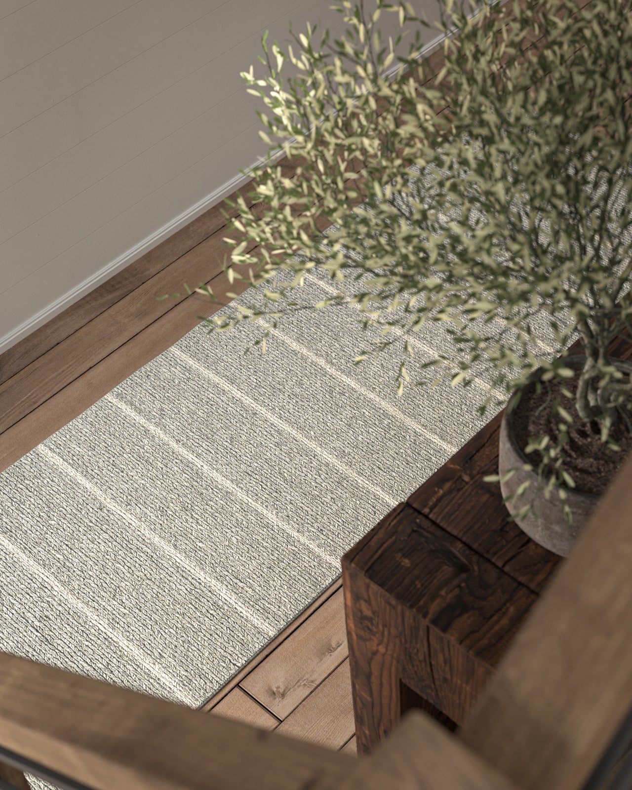 Light gray striped area rug on warm wood floor beside a dark wooden console with a potted plant, 5' x 8'.