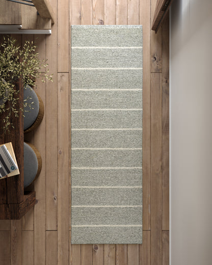 Long gray textured woven area rug with pale horizontal stripes on wooden floor.