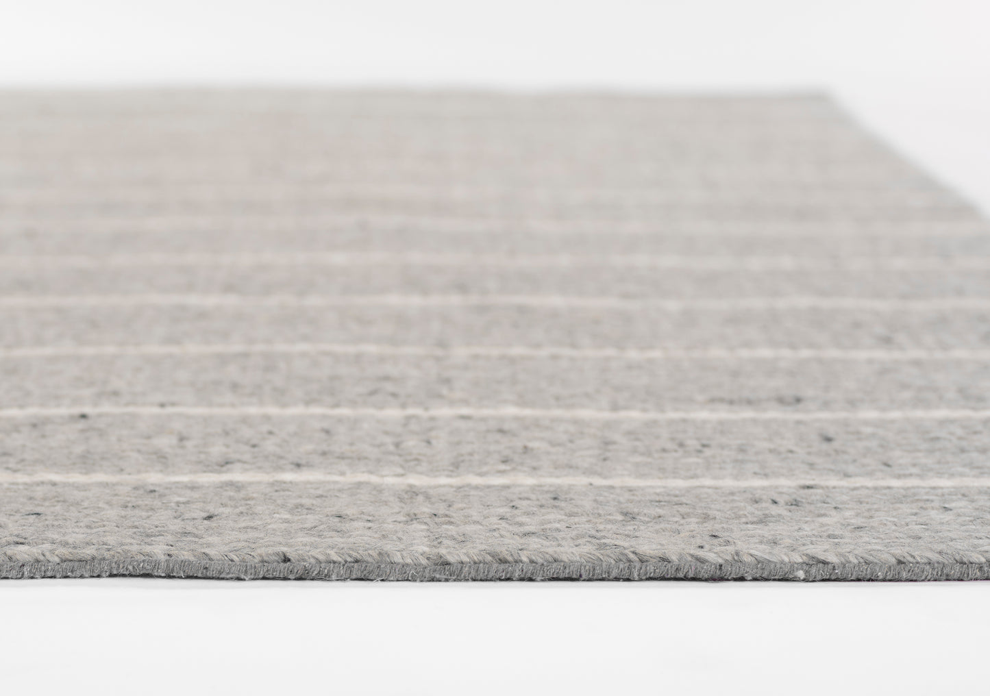 Grey striped rug with soft texture and fringe edge.