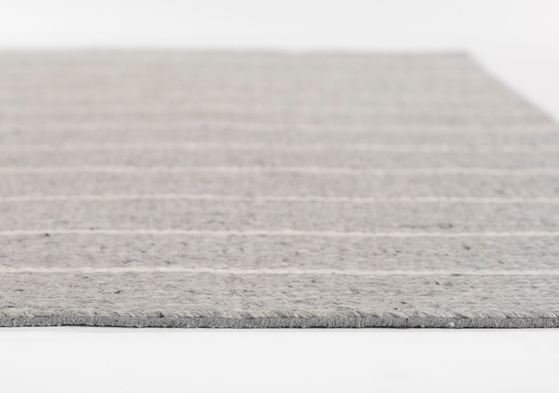 Grey striped rug with soft texture and fringe edge.