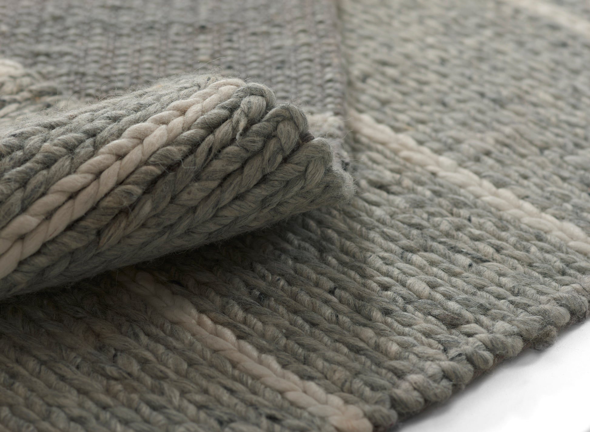Gray chunky braided wool rug with ivory stripe; thick twisted fibers, rolled edge, cozy modern living-room accent.