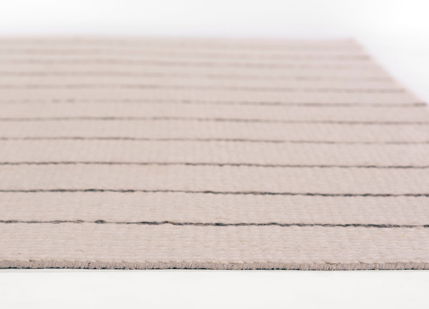Beige woven area rug with dark horizontal stripes and soft, textured low-pile surface.