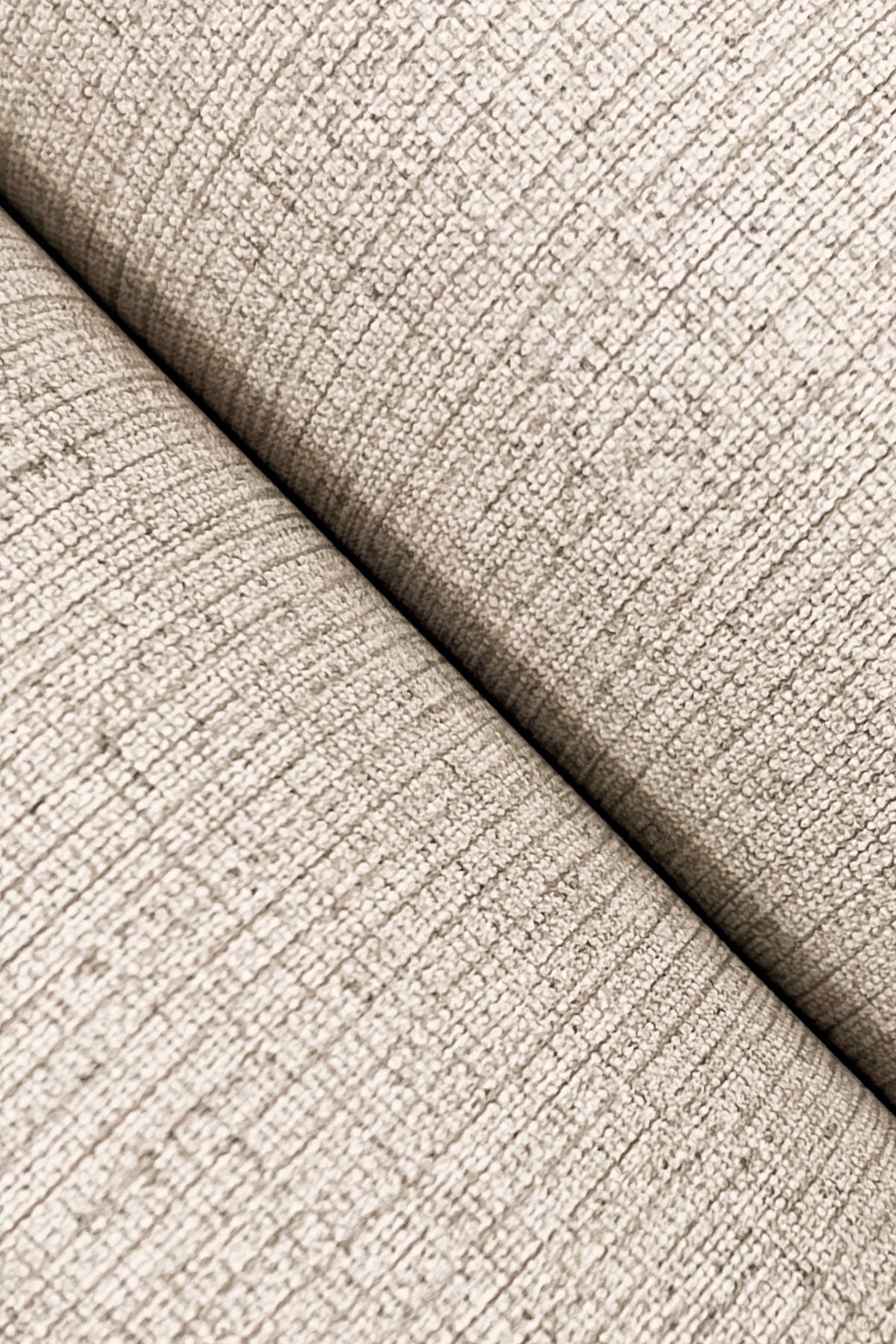 Beige textured wallpaper close-up with subtle linen-jute weave and visible seam.