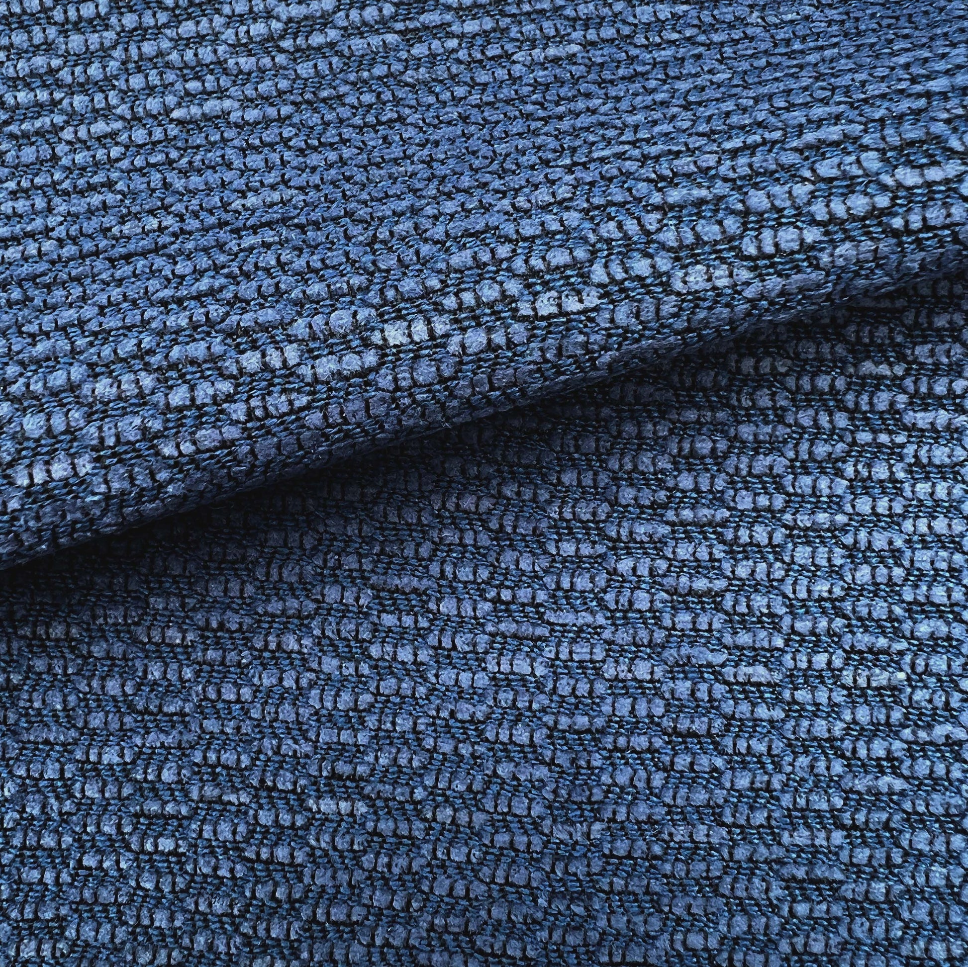 Deep blue textured chenille fabric with a pebble-like weave and folded edge, suitable for upholstery or outdoor use.