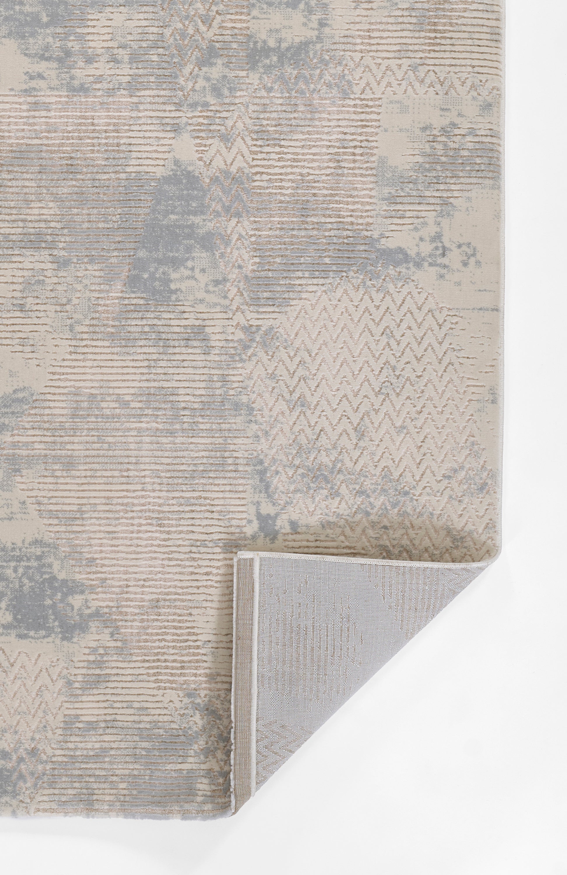 Neutral abstract area rug in beige, gray and taupe with chevron and stripe patterns; folded corner shows woven back.