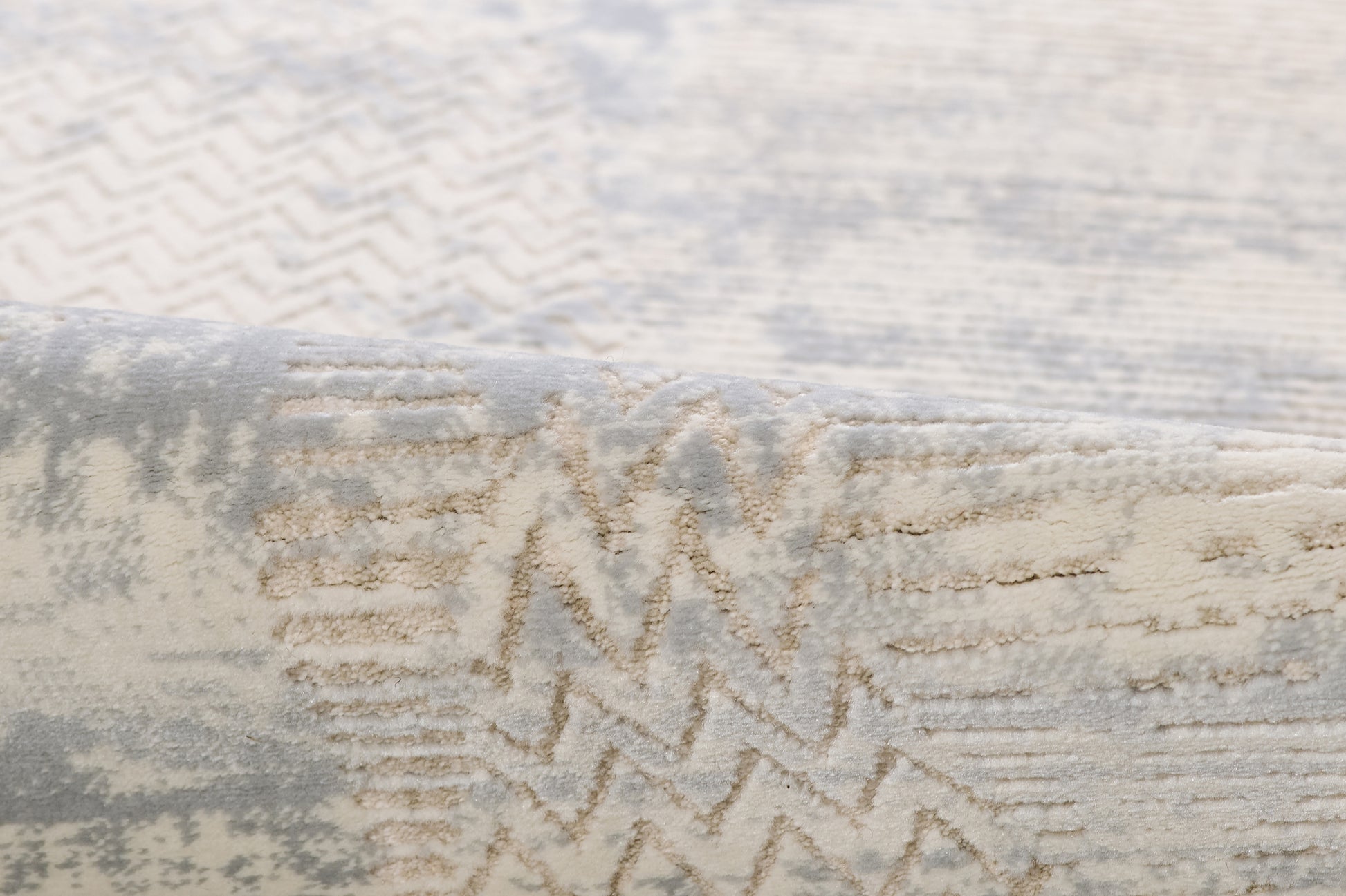 Close-up of a neutral rug with cream & gray zigzag pattern and plush textured pile.
