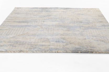 Light blue-gray and beige abstract area rug with chevron patchwork; soft woven texture, rectangular.