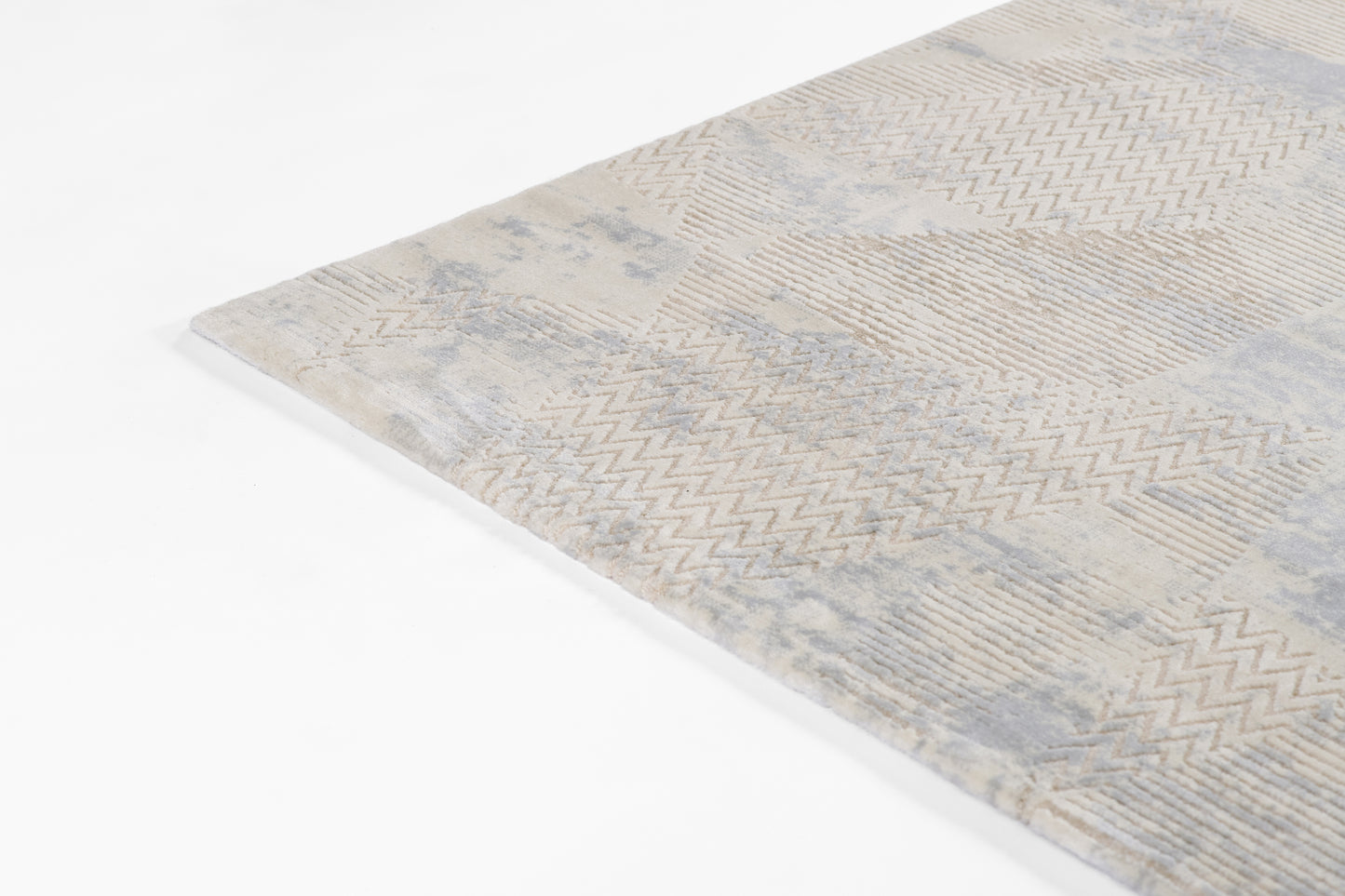 Beige and pale blue geometric rug with chevron and patchwork patterns, soft woven texture.