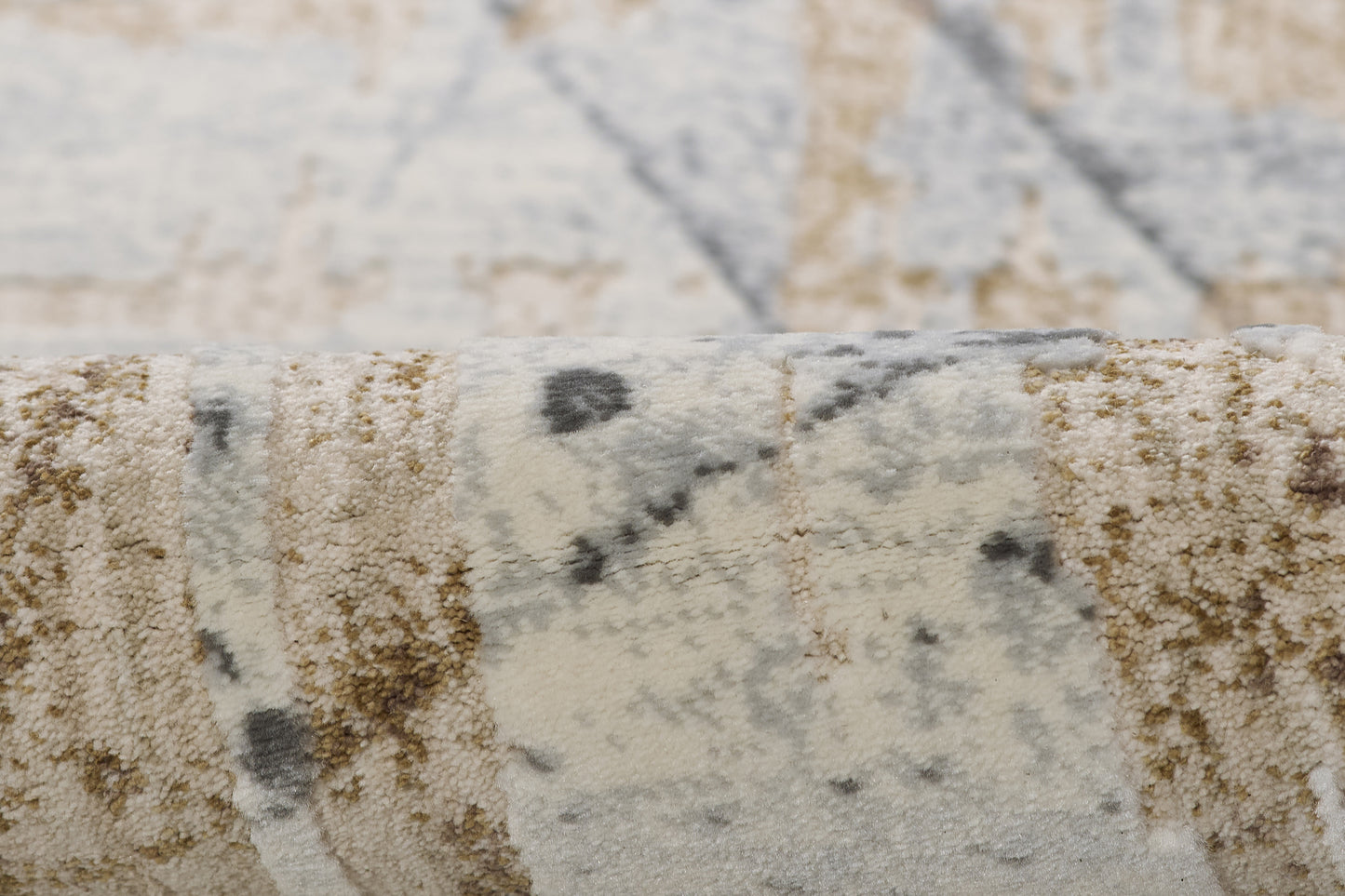 Close-up of a plush abstract area rug in beige, ivory, gray and blue tones.