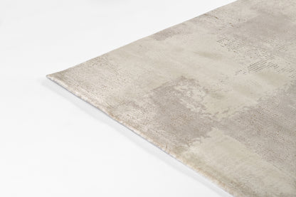 Rectangular beige distressed rug with patchwork pattern and soft, low-pile texture.