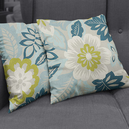 Two decorative throw pillows featuring blue, teal and lime floral patterns on light gray fabric, resting on a gray sofa.
