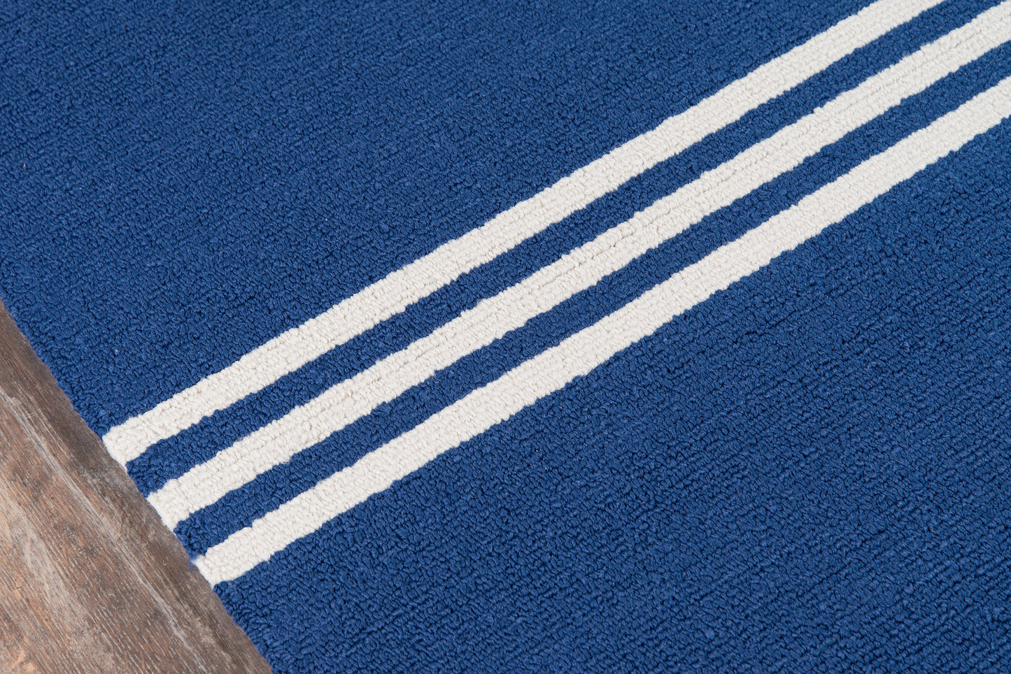 Blue textured area rug with two cream stripes running diagonally; plush pile on wood floor.